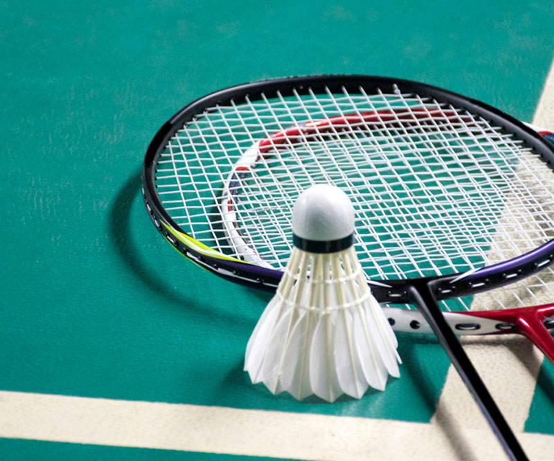 Badminton sport equipments, rackets and shuttlecocks on dark floor of indoor badminton court, soft focus, concept for badminton playing lovers around the world, copy space.